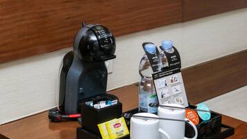 A coffee station with a Keurig coffee maker, water bottles, coffee pods, and a tray with two white mugs.