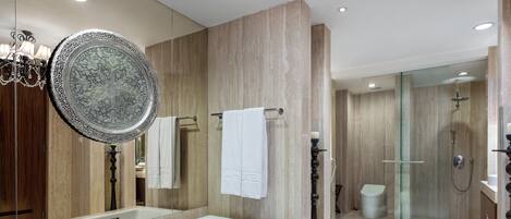 Un baño moderno con una bañera grande, cabina de ducha con mampara de vidrio y un candelabro.