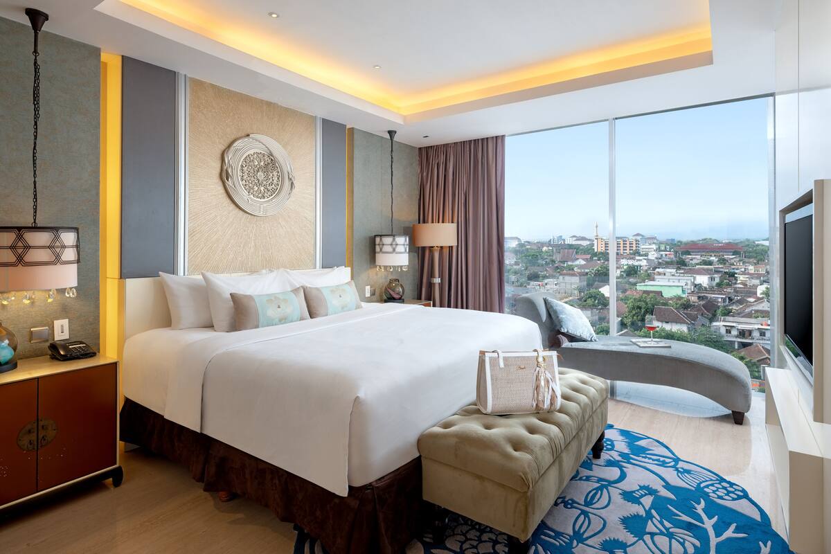 Una habitación de hotel moderna con una cama grande, un escritorio, una silla y vistas a la ciudad.