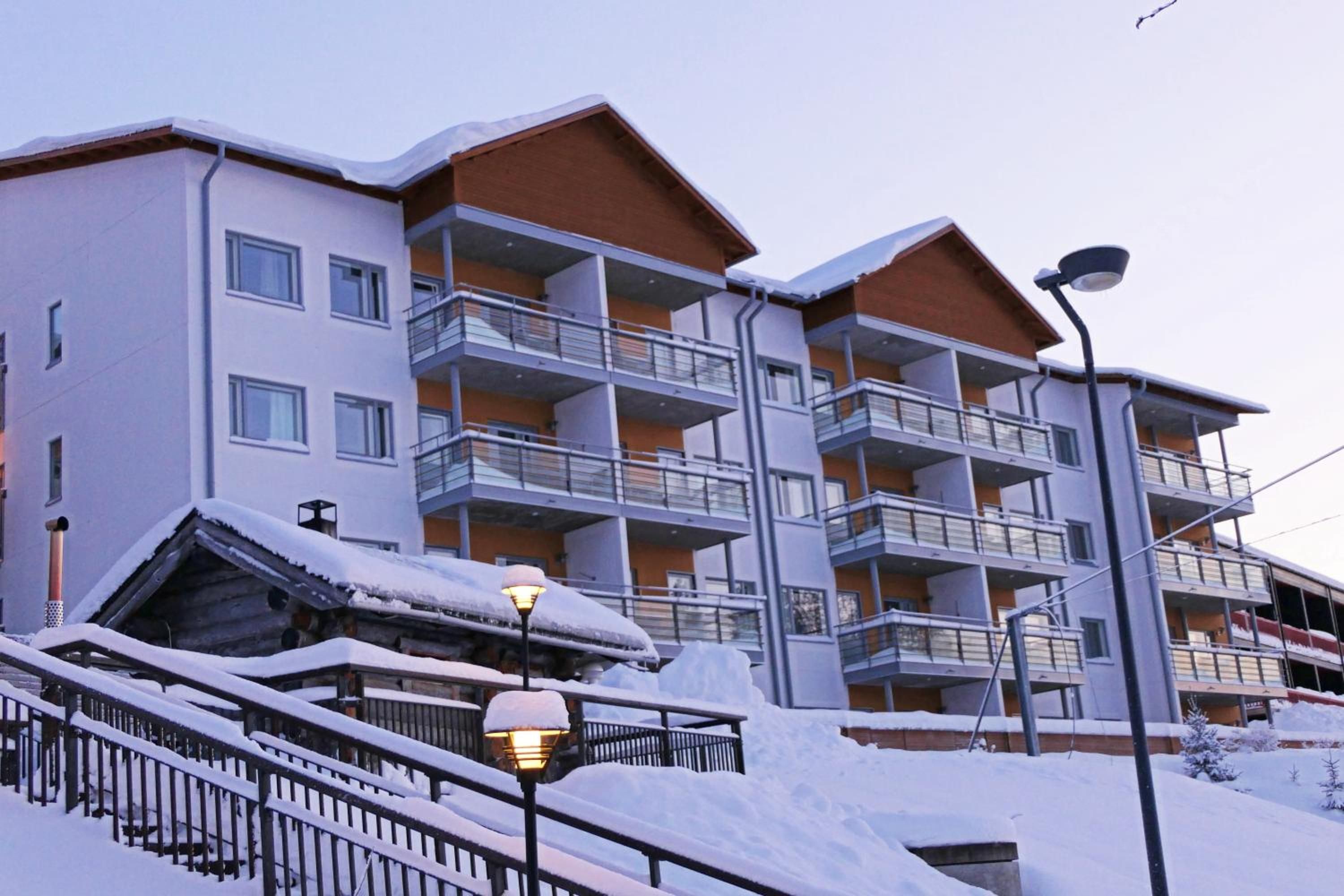 A multi-story hotel with balconies, a snow-covered roof, and a street lamp.