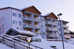 A multi-story hotel with balconies, a snow-covered roof, and a street lamp.