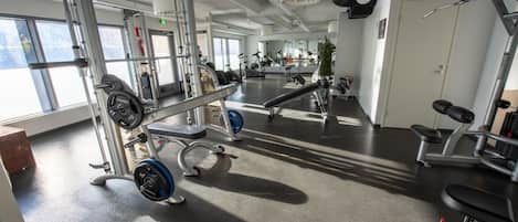 Een fitnessruimte met gewichthefapparatuur, loopbanden en trainingsmachines.