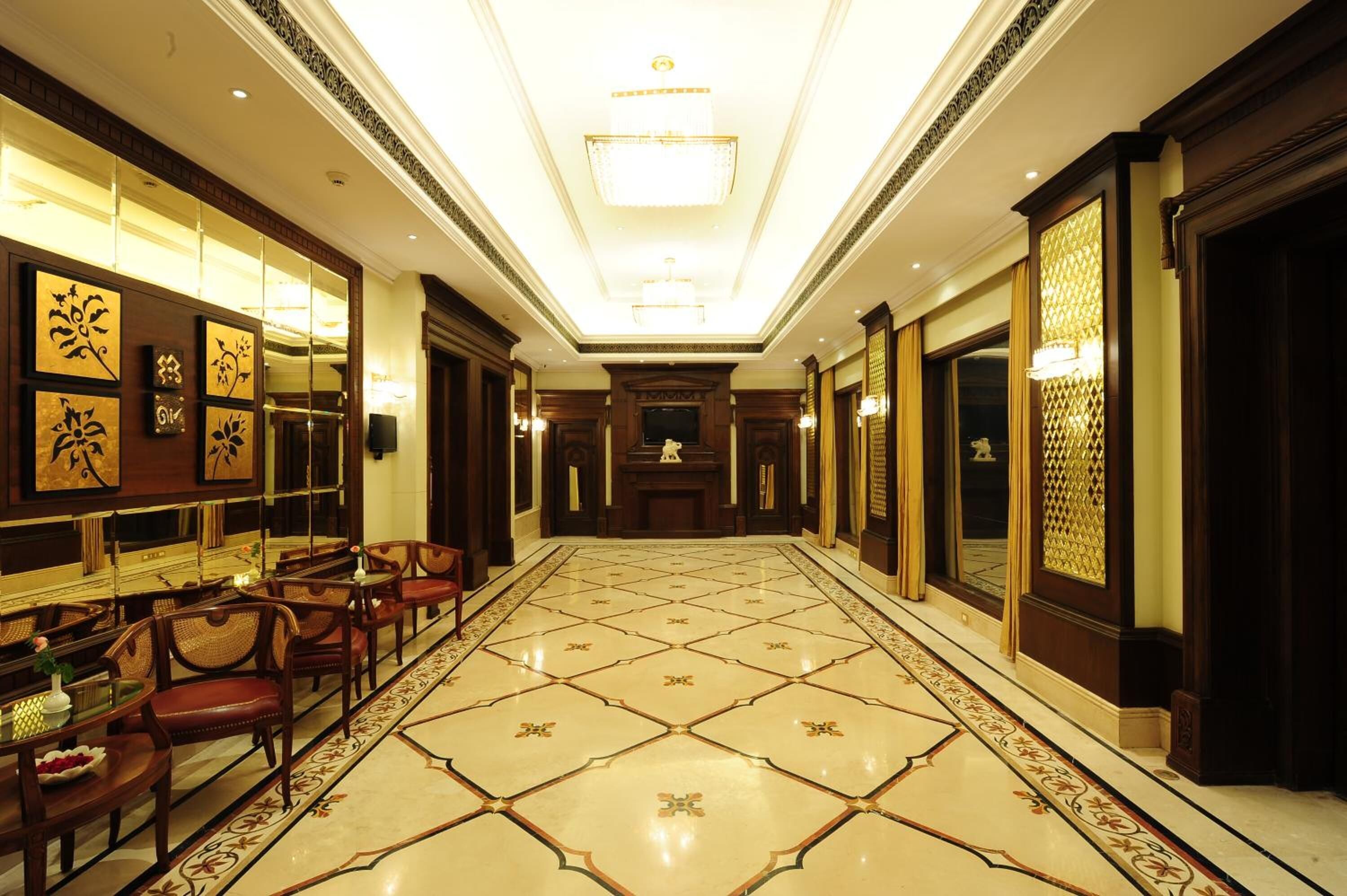 Vestíbulo de hotel con un largo pasillo, decoraciones ornamentales en las paredes y un candelabro.