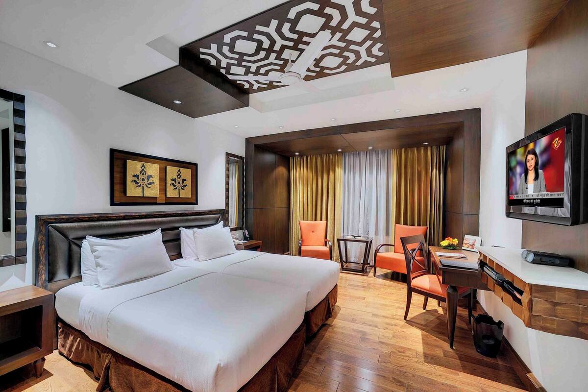 A hotel room with a large bed, a desk with a chair, a television, and a view of the outdoors.