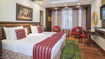 Una habitación de hotel con una cama grande, dos sillas rojas, un escritorio y un espejo amplio.