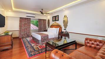 A hotel room with a bed, a sofa, a coffee table, a TV, and a ceiling fan.