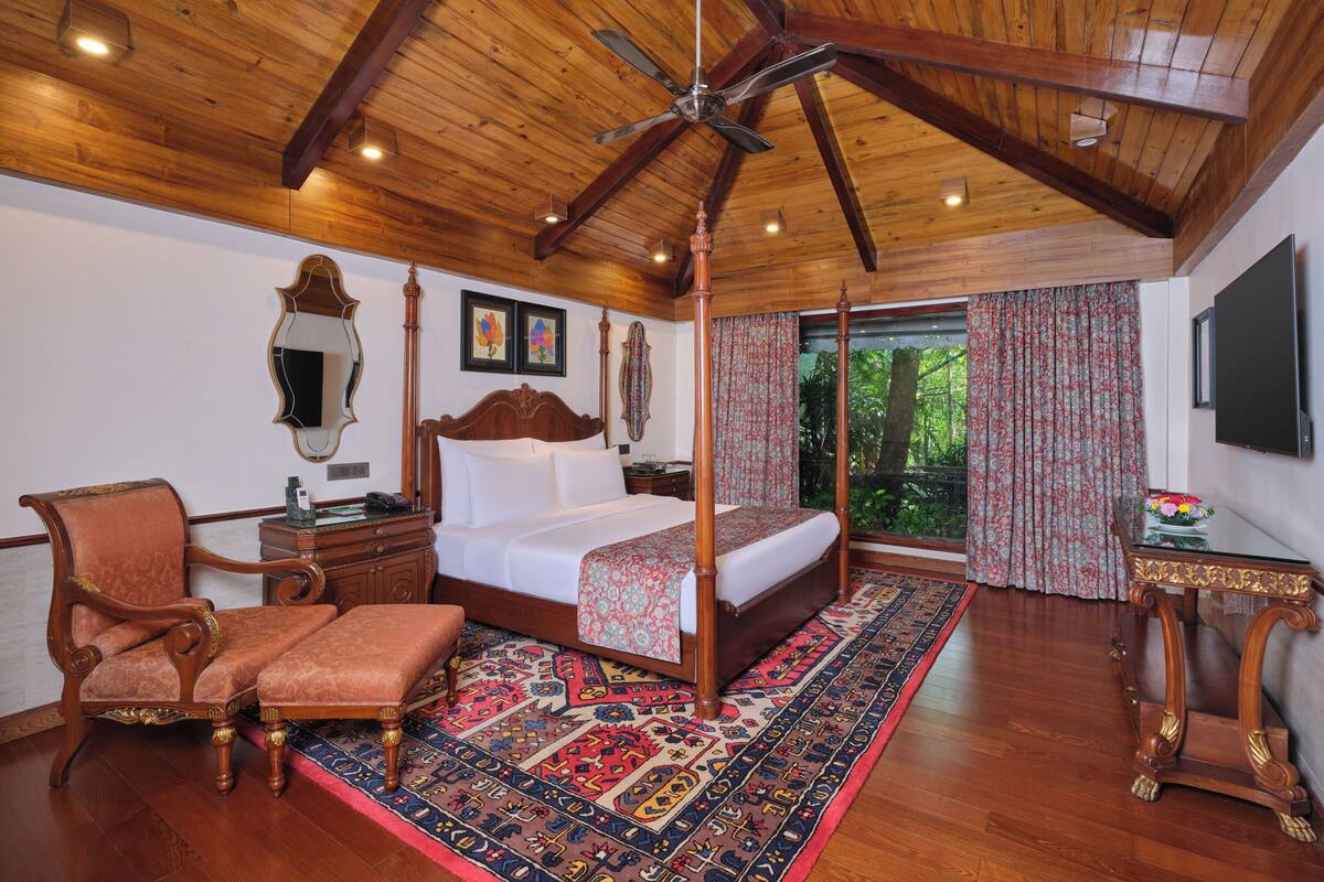 A four-poster bed with a canopy, a wooden desk, a chair, and a large mirror on the wall.