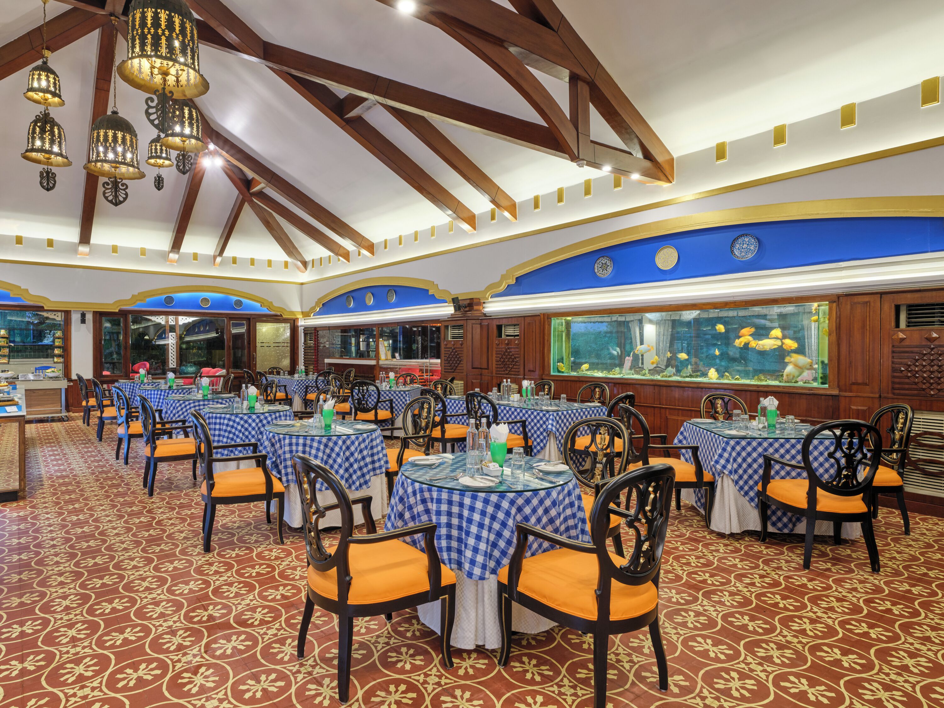 A restaurant with multiple tables, chairs, and a large fish tank.