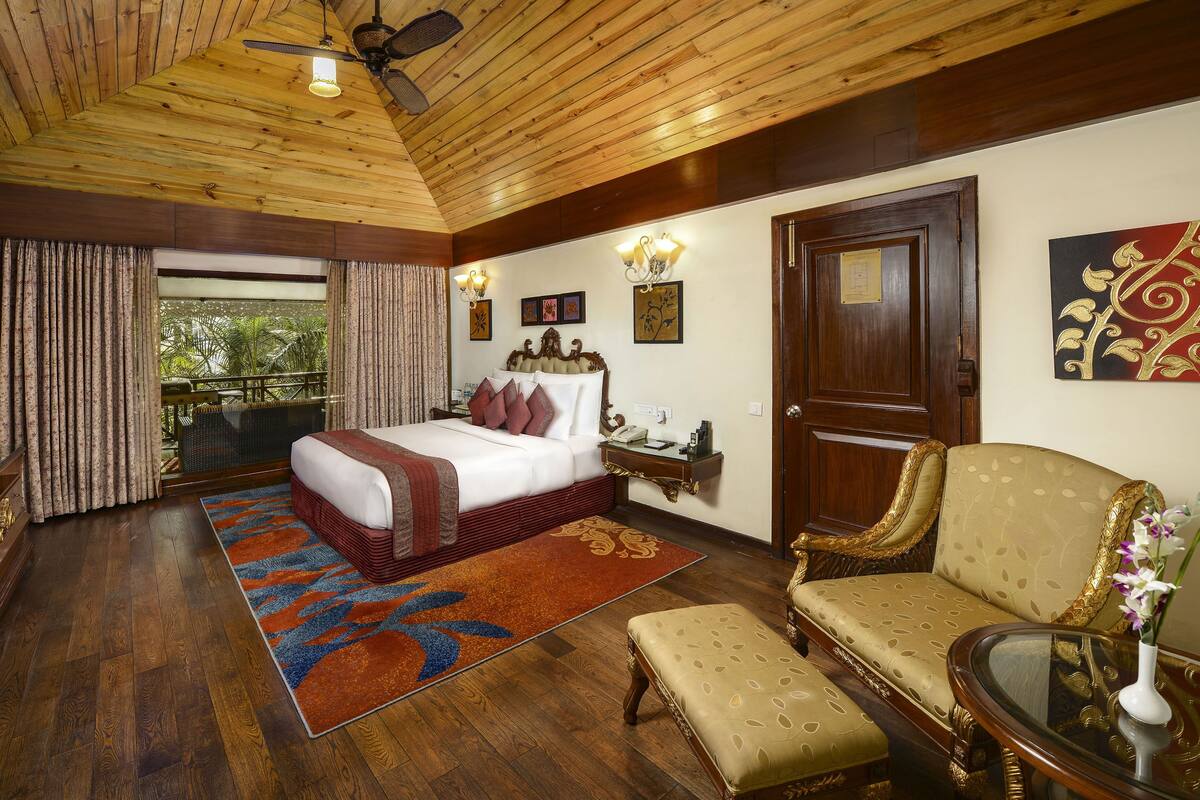 A spacious bedroom with a large bed, a sitting area, and a view of the outdoors.