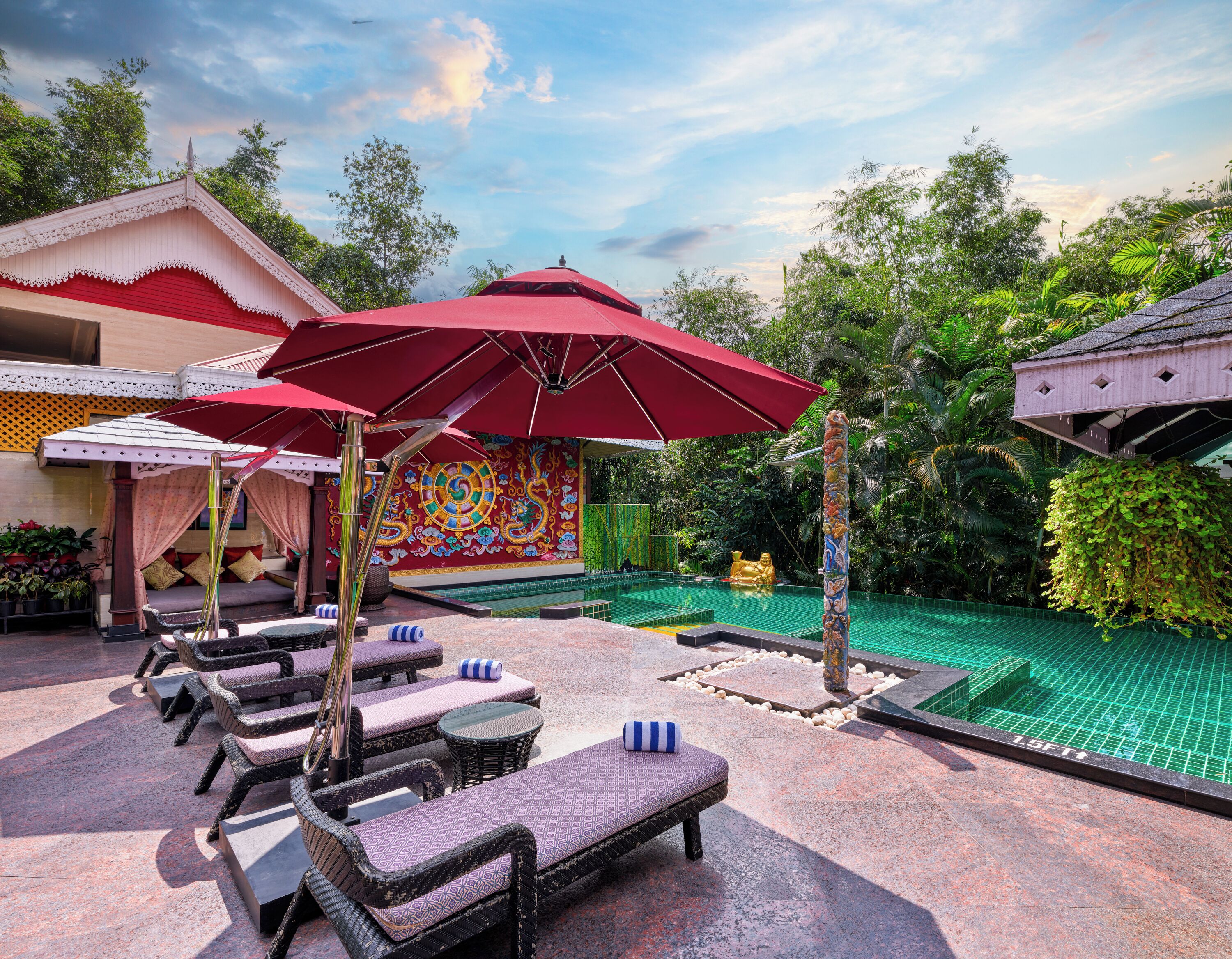 A poolside area with lounge chairs, a red umbrella, and a decorative wall.