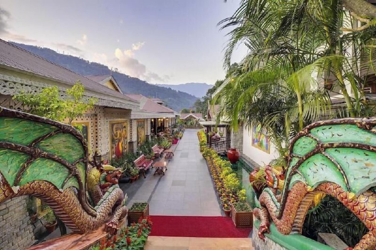 Um caminho ladeado por esculturas de dragões que leva a um edifício com arquitetura tradicional.