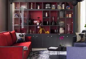 Una sala de estar moderna con un sofá rojo, una mesa de centro negra y una estantería llena de diversos objetos.