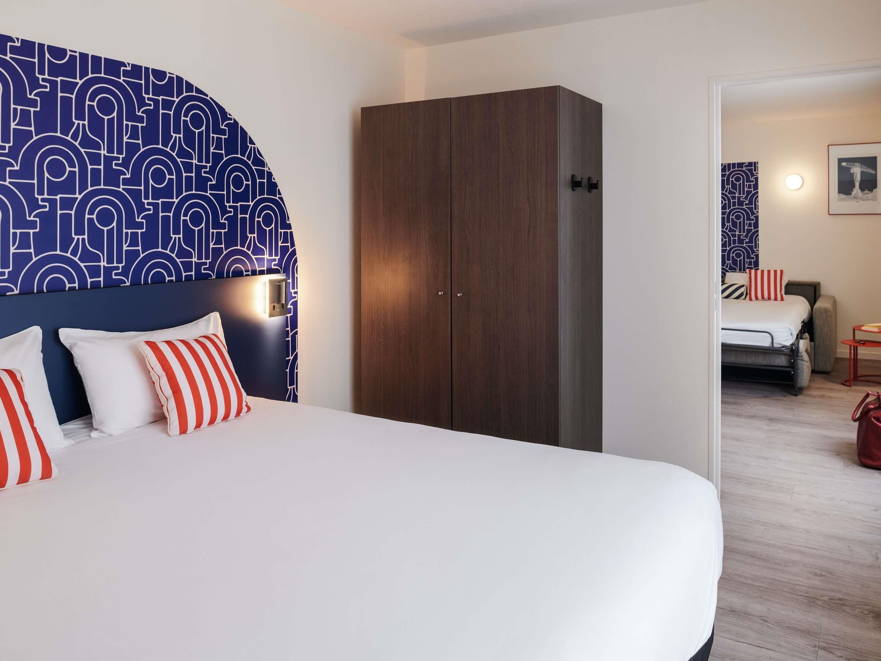 Ett hotellrum med en stor säng, en garderob och utsikt in i ett annat rum.