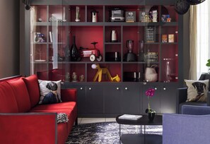 Ein modernes Wohnzimmer mit einem roten Sofa, einem schwarzen Couchtisch und einem Bücherregal voller verschiedener Gegenstände.