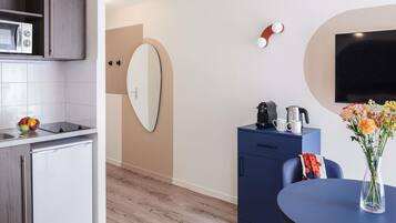 A modern kitchen with a microwave, a small refrigerator, and a dining area with a table and chairs.