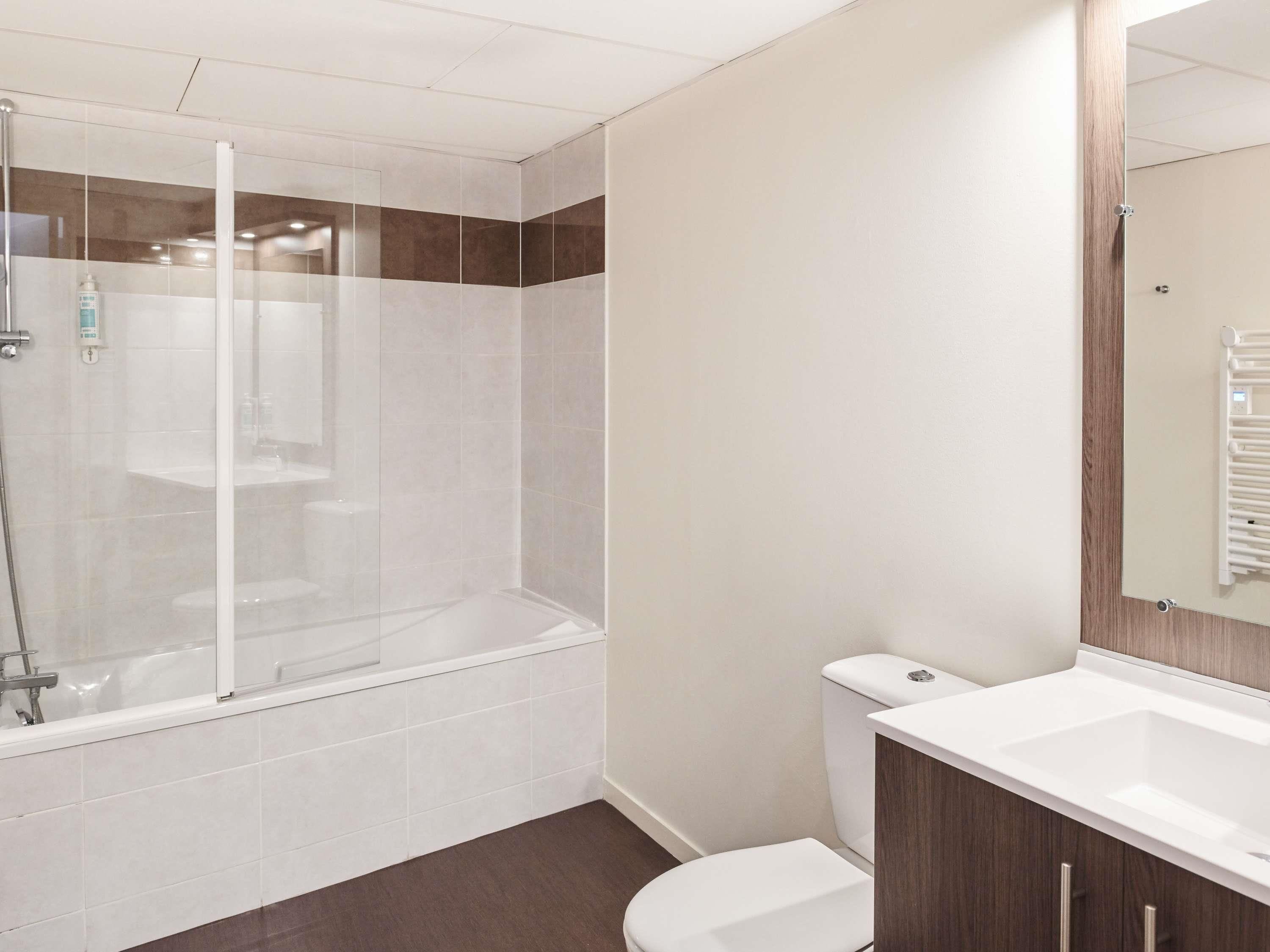A modern bathroom with a glass-enclosed shower, a white toilet, and a vanity with a mirror.