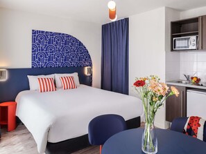A hotel room with a bed, bedside table, chair, and a small dining area with a table and chairs. - Aparthotel Adagio Access Nantes Viarme (Nantes)