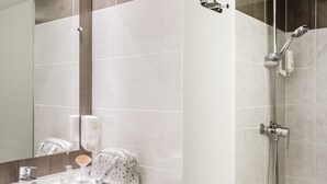 Un baño moderno con ducha, lavamanos y espejo.