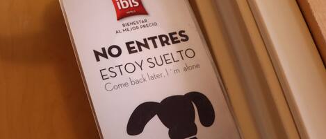 A hotel room's minibar with a minibar key card holder and a message in Spanish.