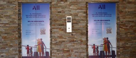 Dos carteles grandes en una pared de ladrillo publicitando un programa de fidelización con un 10% de descuento en más de 5000 hoteles a nivel mundial.