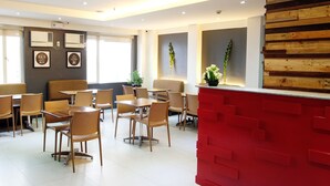 Un comedor moderno con sillas y mesas de madera, una barra roja y carteles sobre salud enmarcados en las paredes.