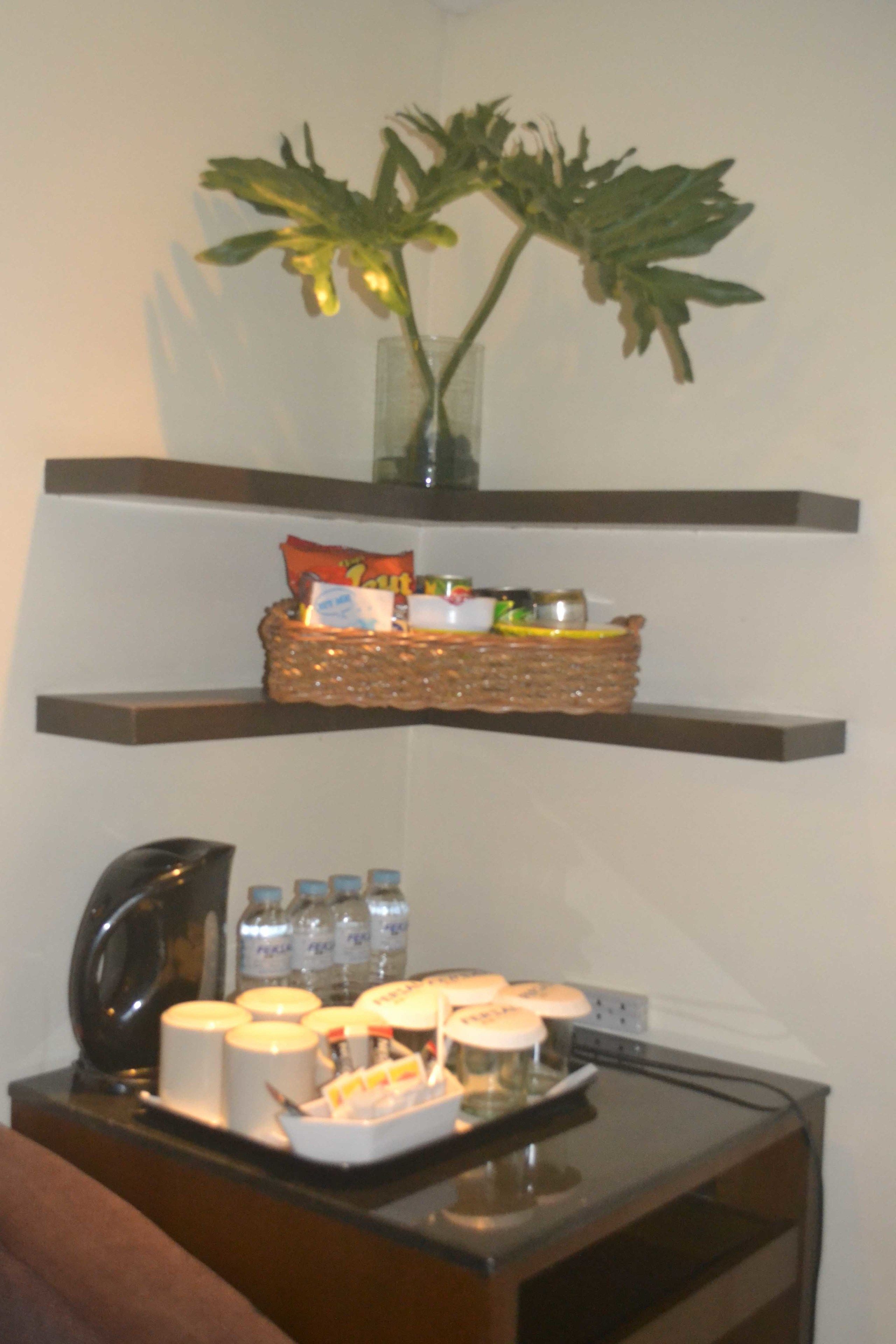 Un comptoir de cuisine avec une machine à café, un panier de collations et un vase avec une plante.