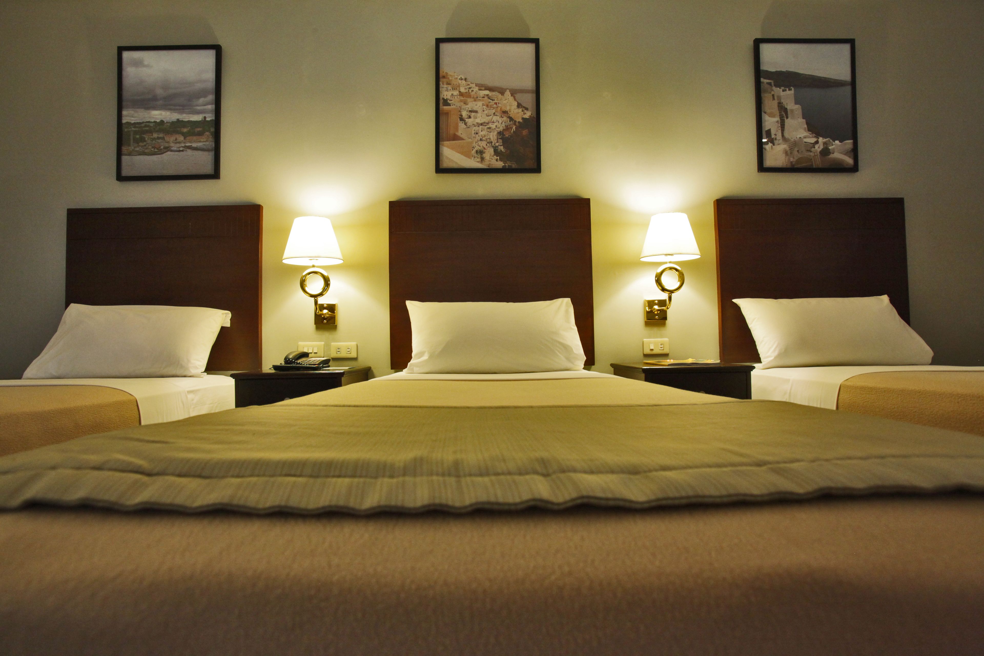 Ein Hotelzimmer mit einem großen Bett, zwei Nachttischen und drei Wandlampen.
