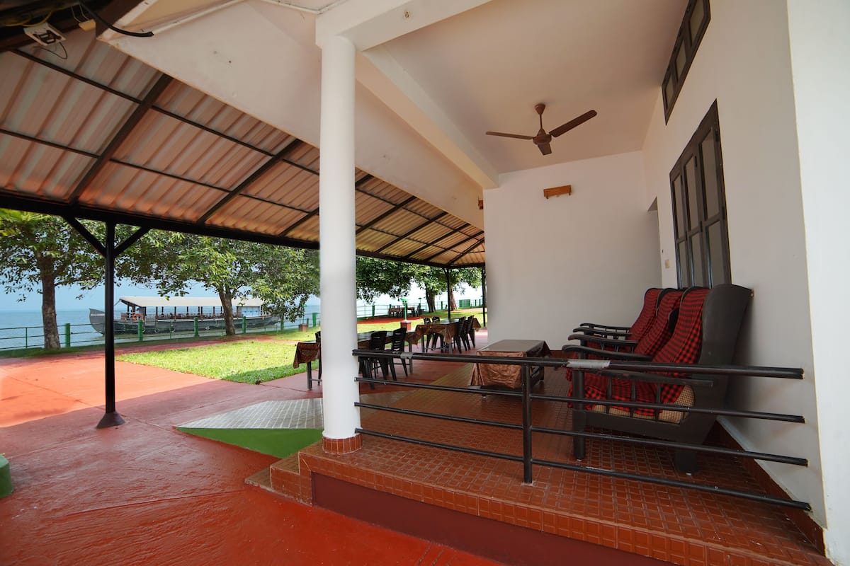 A covered outdoor seating area with tables and chairs, a ceiling fan, and a view of the sea.