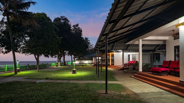 A hotel with a covered outdoor seating area, a pool, and a view of the sea. - ILLIKKALAM Lakeside Cottages Kumarakom Kerala (Kottayam)