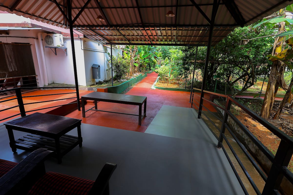 A covered outdoor area with a bench, a table, and a pathway leading to a garden.