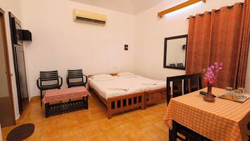 A room with a bed, two chairs, a table with a checkered tablecloth, a mirror, and a curtain.