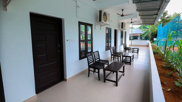 A covered outdoor area with seating, ceiling fans, and air conditioning units. - ILLIKKALAM Lakeside Cottages Kumarakom Kerala (Kottayam)