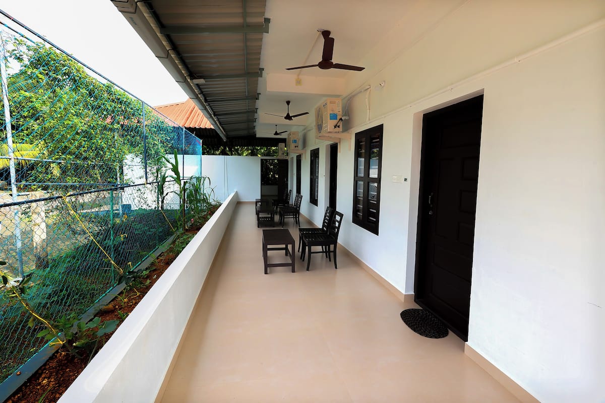 A covered balcony with a table and chairs, a black door, and ceiling fans.