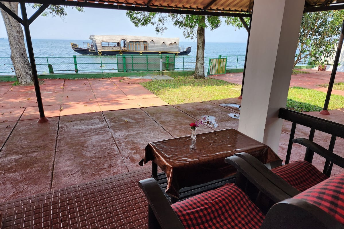 A covered outdoor seating area with a view of the sea and a boat.