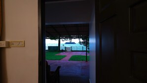 An open doorway leading to a covered outdoor area with a view of the sea. - ILLIKKALAM Lakeside Cottages Kumarakom Kerala (Kottayam)