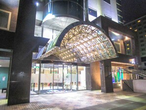 En hotelindgang med et karakteristisk buet glasoverdækning og et moderne design.