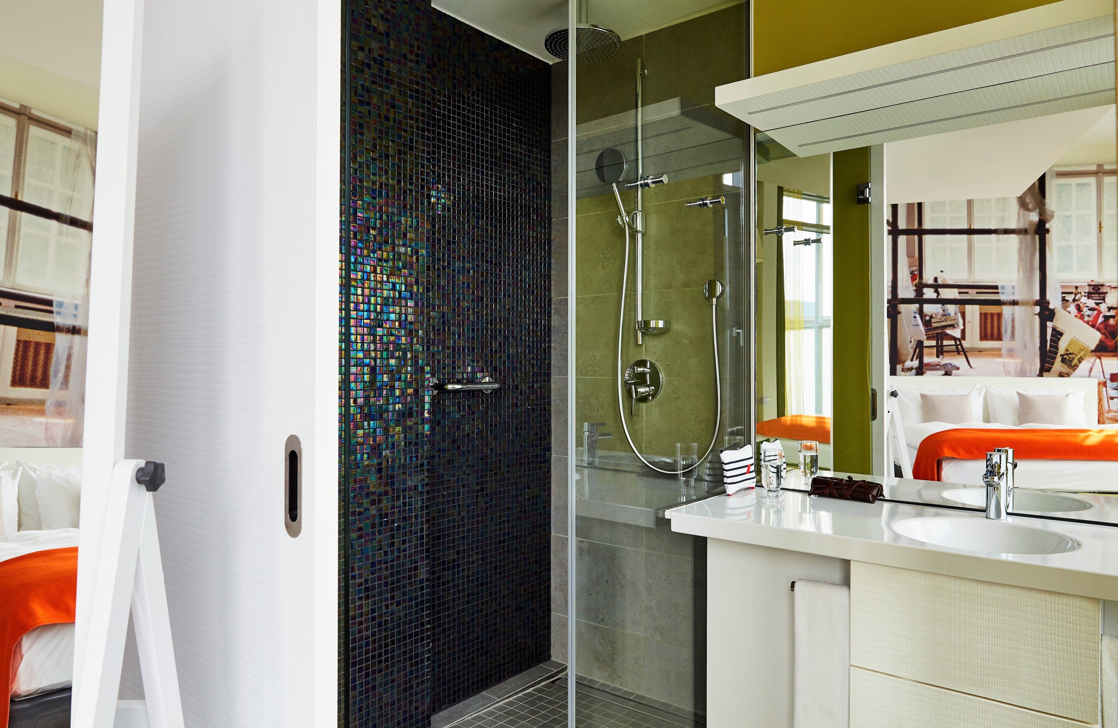 Un baño moderno con cabina de ducha de vidrio, un lavabo blanco y un espejo.