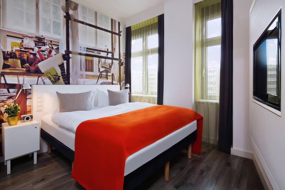 Une chambre à coucher moderne avec un lit, une table de chevet et un téléviseur.