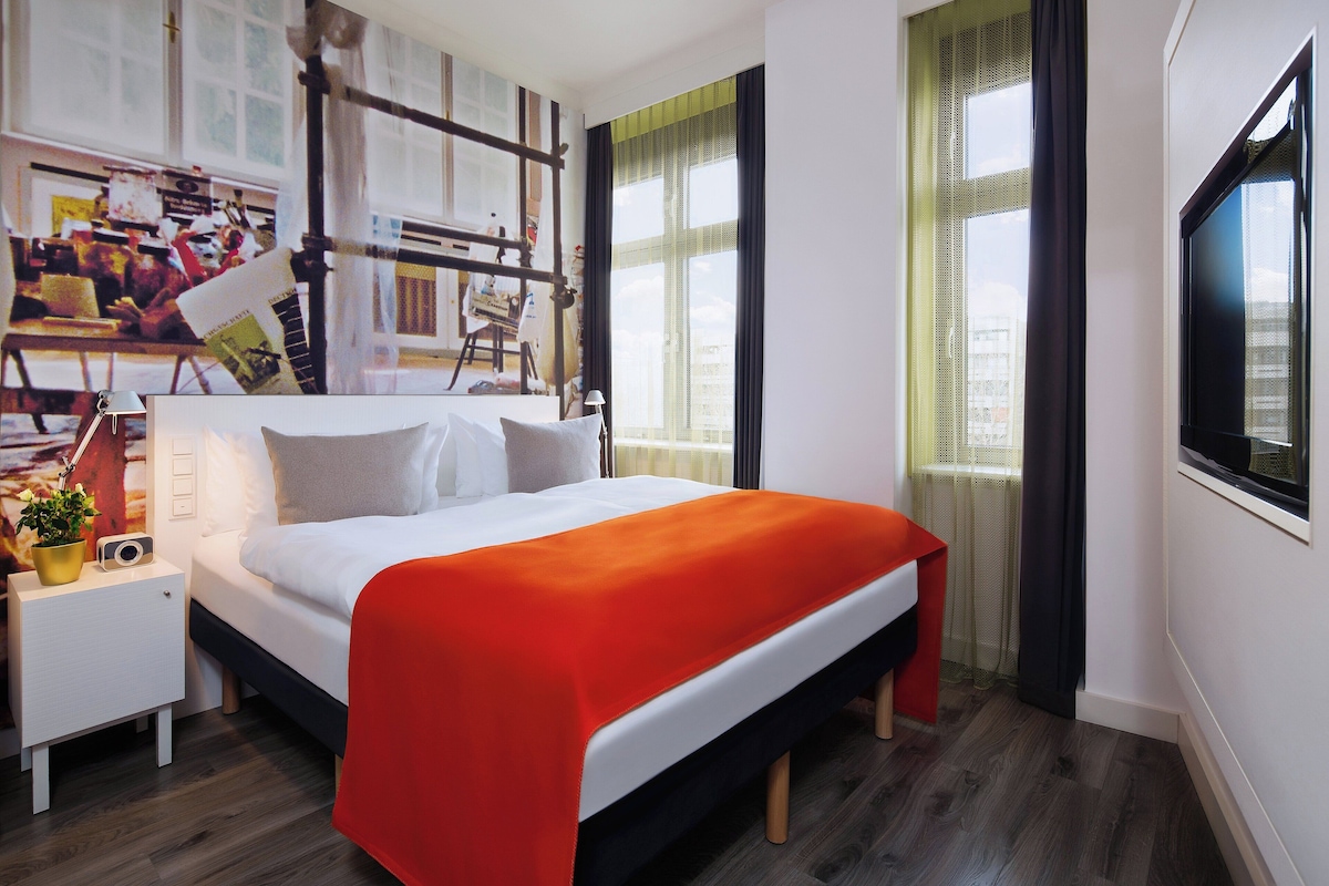 Une chambre à coucher moderne avec un lit, une table de chevet et un téléviseur.