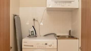 Un lavadero pequeño con lavadora, secadora y un lavamanos.