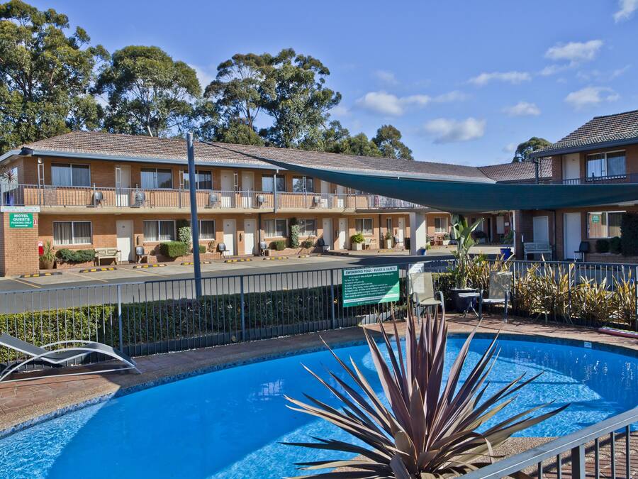 Ein Hotel mit Schwimmbad, Außenbereich und Hinweisschild für Schwimmbad, Pool und Grillplatz.