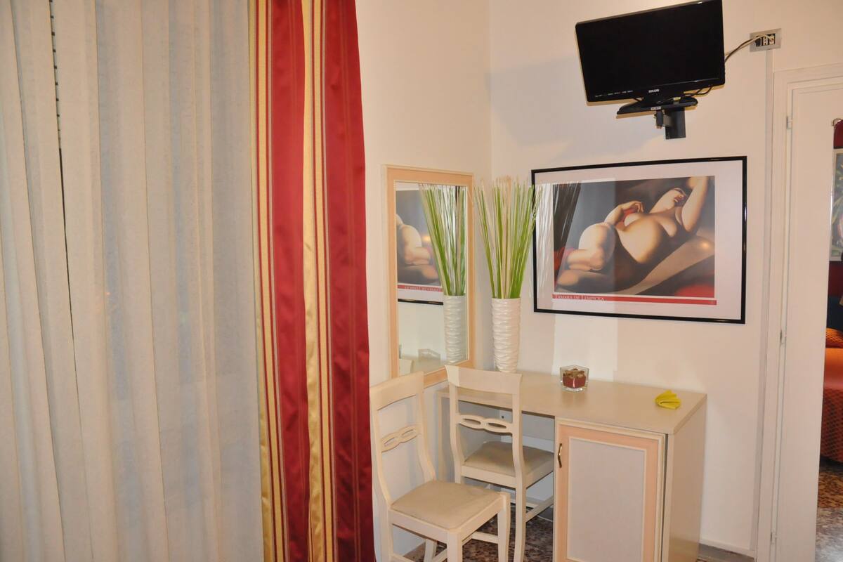 A room with a desk, chairs, a television, and artwork on the wall.