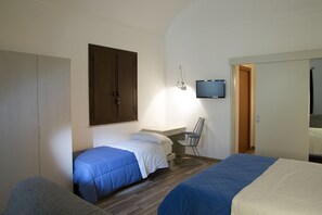 Een slaapkamer met twee bedden, een bureau, een stoel en een tv die aan de muur is bevestigd.