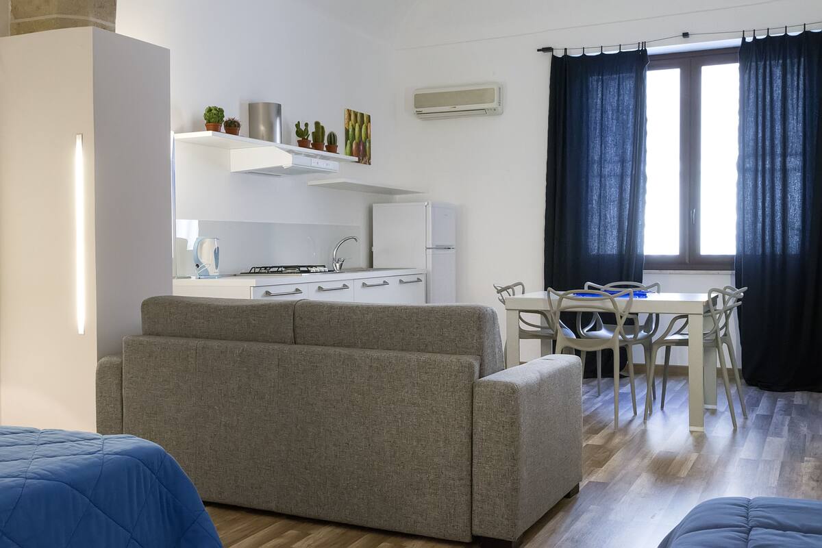 A compact living space with a kitchenette, a dining area, and a sofa.