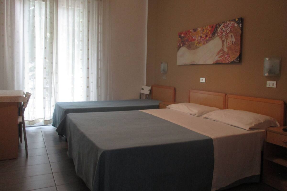 Habitación de hotel con dos camas, un escritorio y un cuadro en la pared.