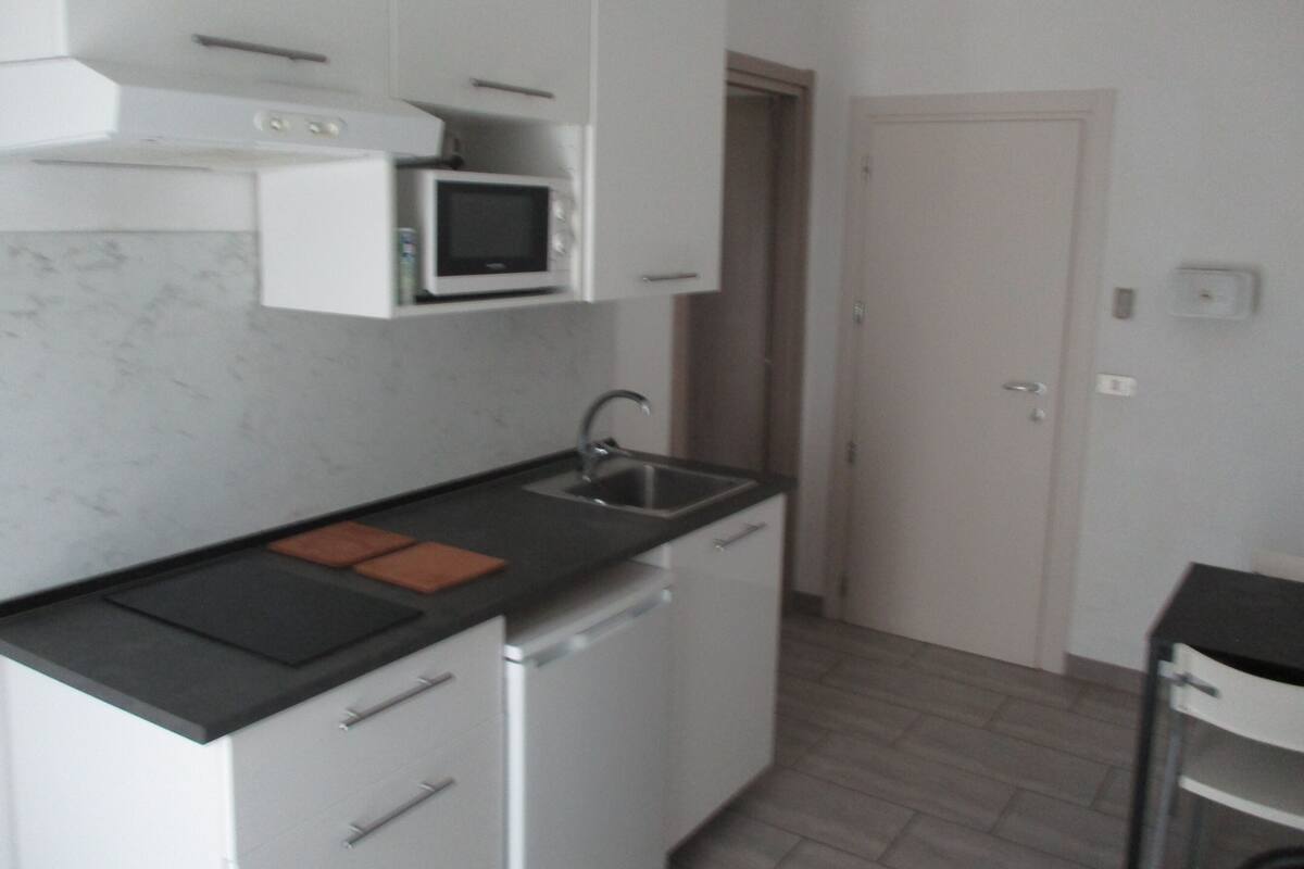 Cocina compacta con alacenas blancas, microondas, pileta y lavavajillas.