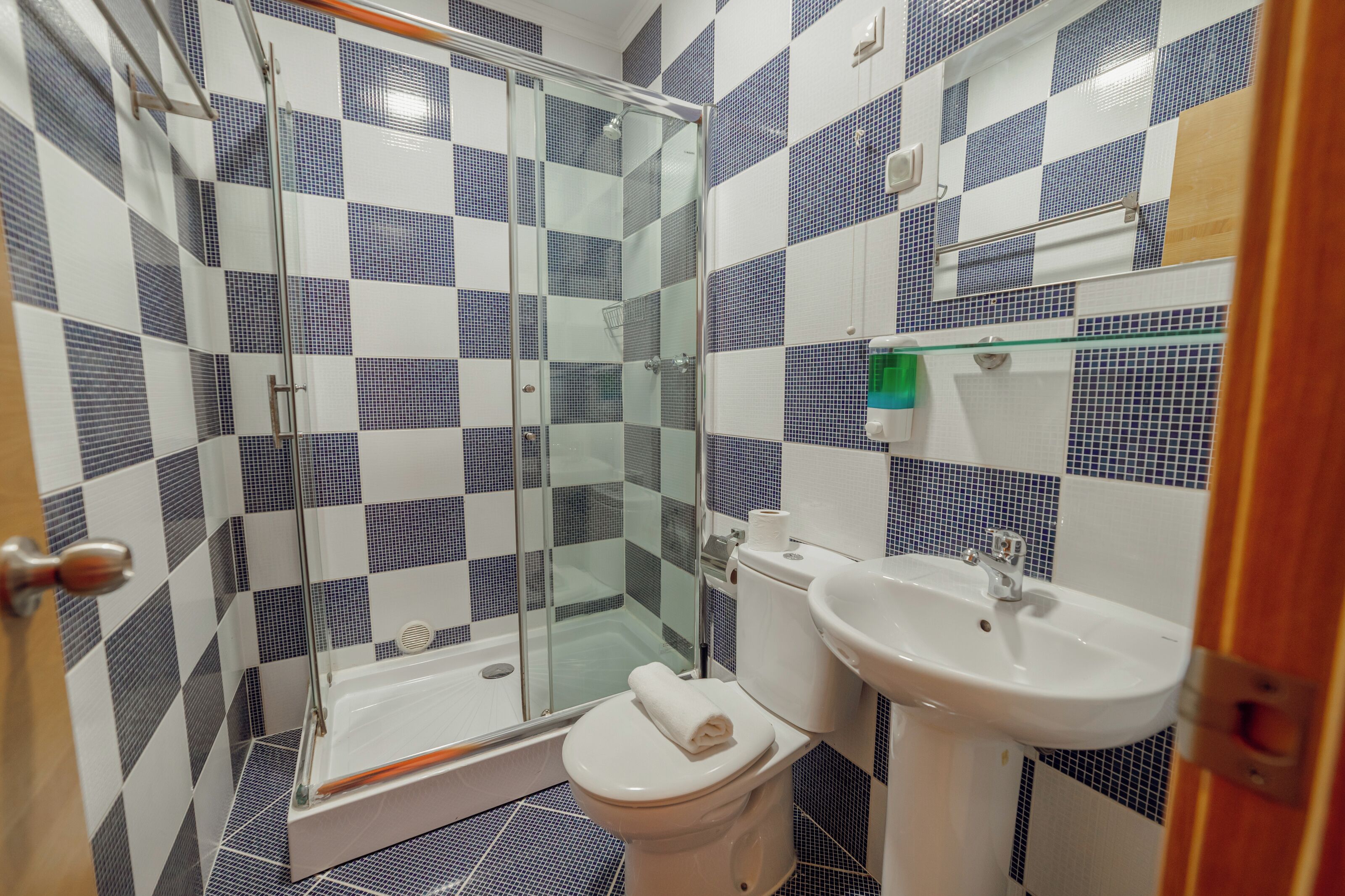 A bathroom with a glass shower enclosure, a white toilet, and a sink.