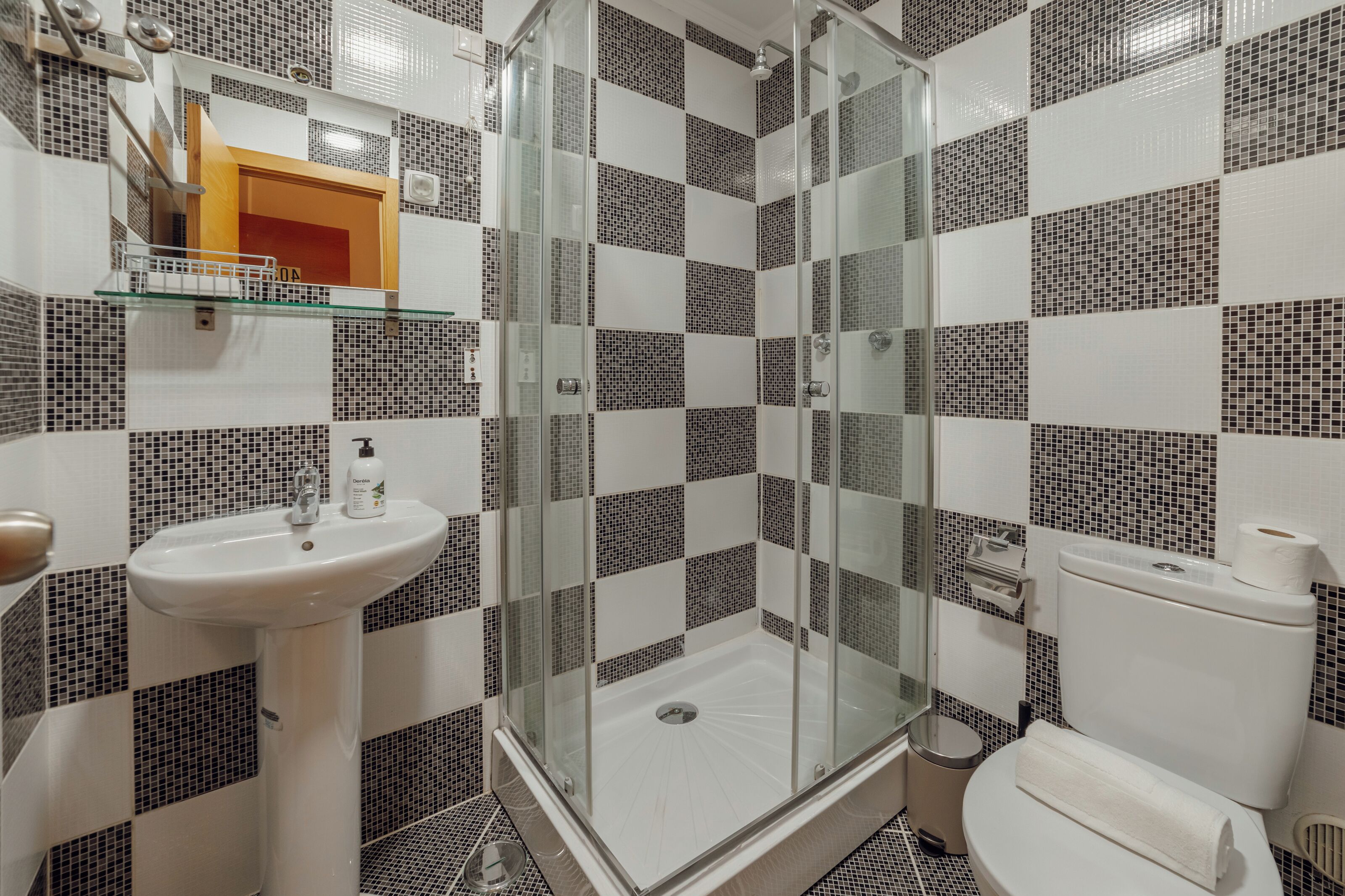 Ein Badezimmer mit einer Duschkabine, einem Waschbecken und einer Toilette.