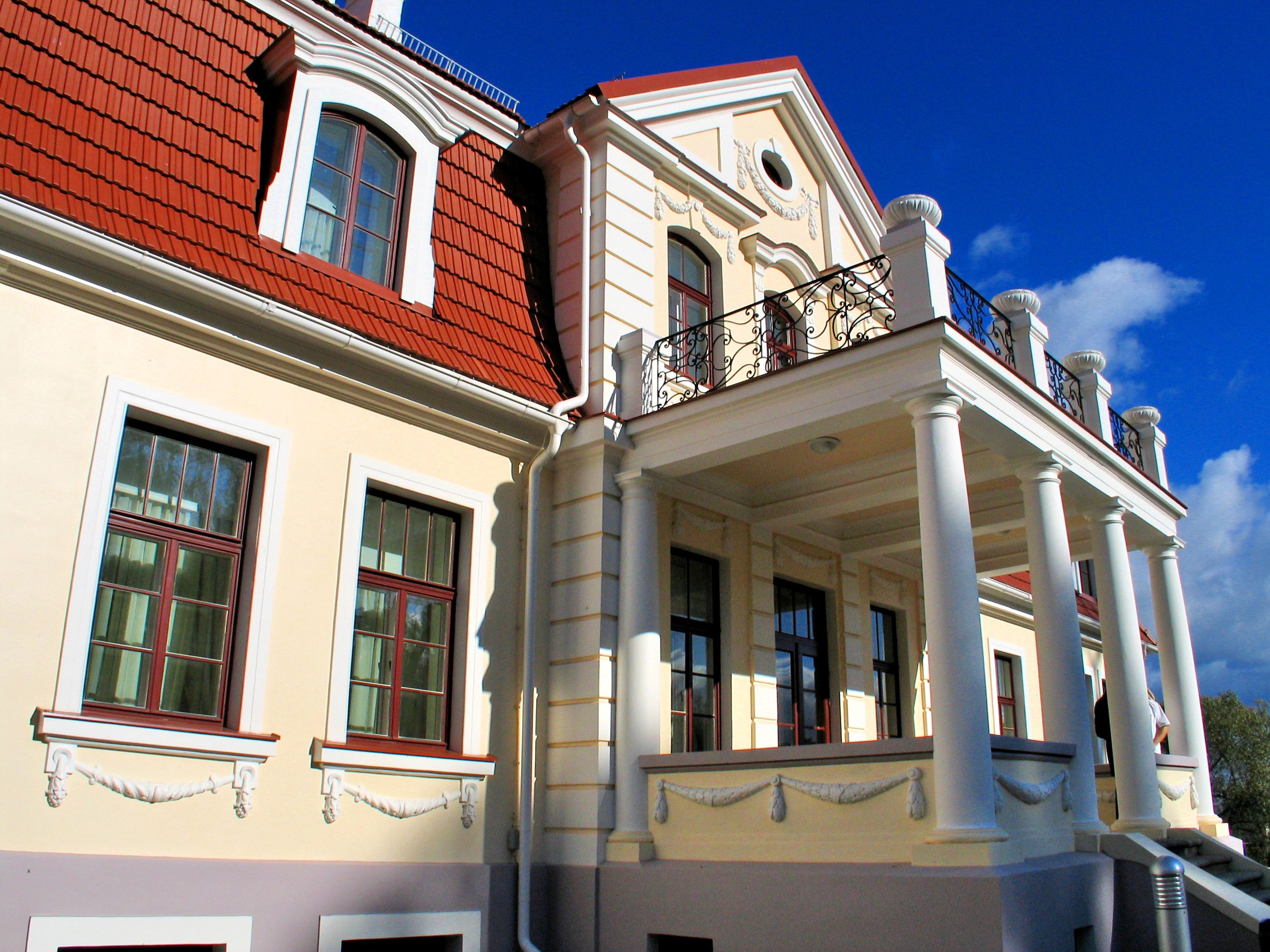 Un bâtiment doté d’un toit rouge, de colonnes blanches et d’un balcon orné d’une balustrade en fer forgé.