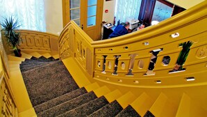 Una gran escalera con barandilla amarilla y un rellano alfombrado.